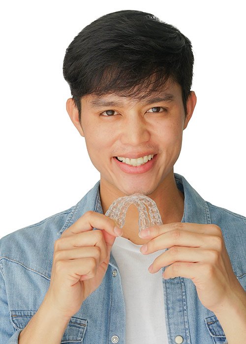 Smiling asian man, holding clear aligners